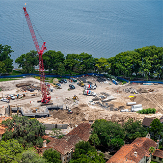 a picture of a lakefront construction site with a red crane